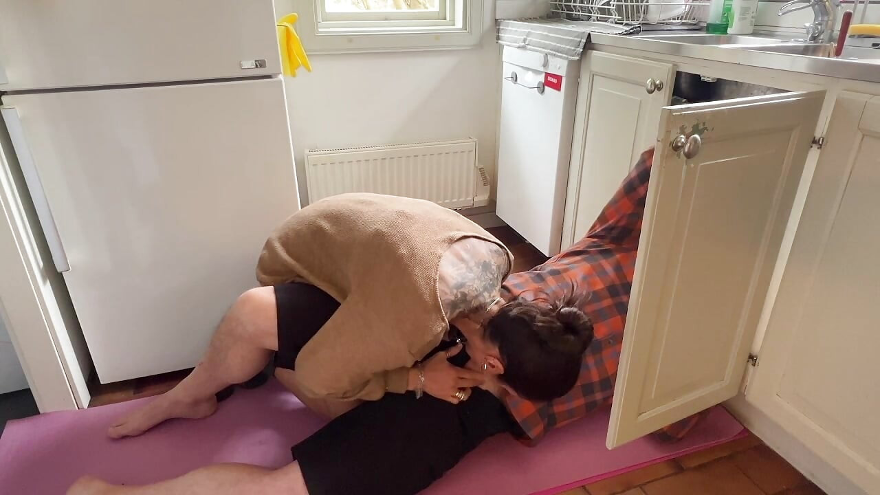 家庭主妇看到水管工在水槽里工作变得饥渴