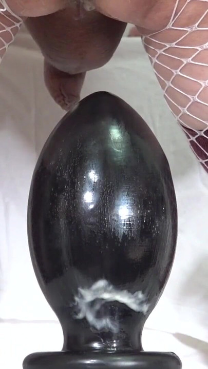 Iconic moment from "White Fishnet Sissy #14 - Riding a huge 95mm anal plug placed on a chair -"