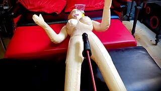 Şişme bir sarışınla sikişiyor ve güçlü bir seks makinesi onu götten sikiyor, inliyor ve seks odasının her yerinde seks kokluyor.