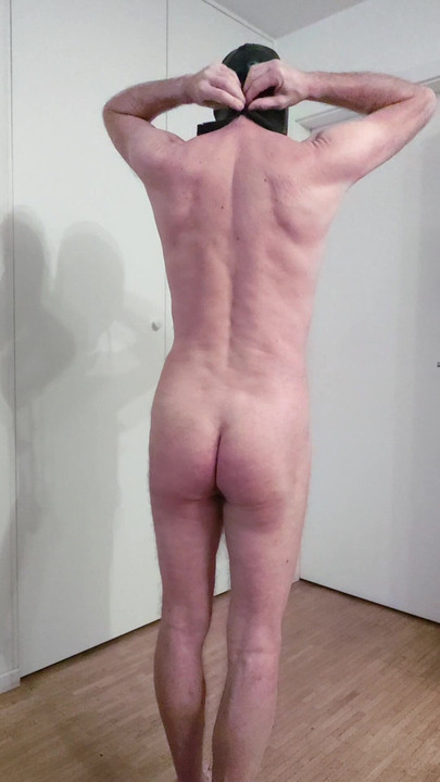 The first fitting of the latex mask without eye openings, but with nasal tubes and an inflatable gag.