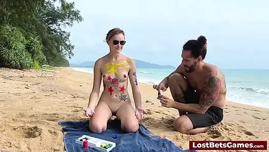 A horny couple playing strip tic tac toe on the beach