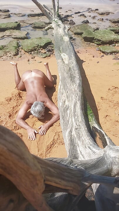 Ladysilva på stranden naken och visar upp sin solbrända sexiga rumpa