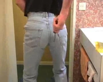 Guy ripping and tearing his pale bue Levi 501 jeans