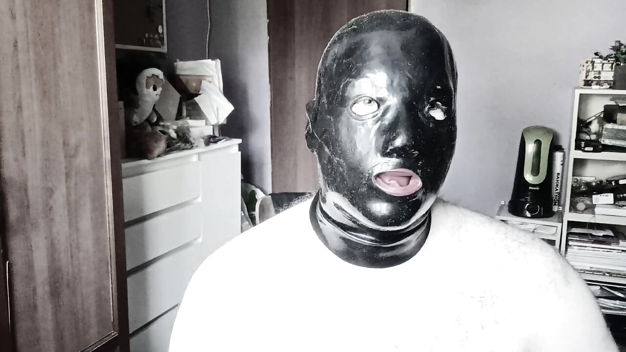 A guy in a latex mask with tubes for his nose jerks off and cums