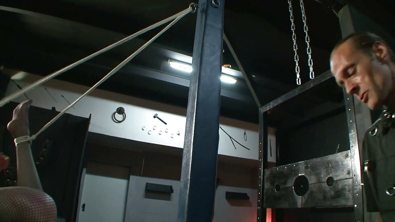 Zamaskowana niewolnica zawieszona w brutalnym łańcuchowym bondage'u