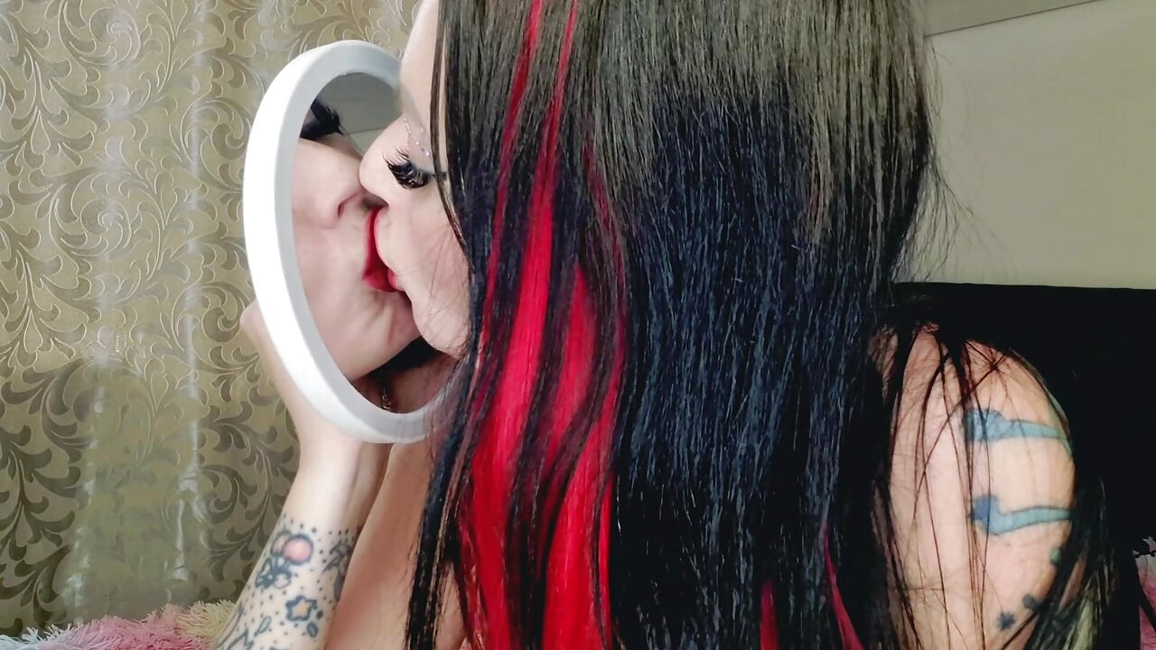 Fetiš ljubljenja, fetiš na crveni ruž za usne. Dominatrix strastveno ljubi svoj odraz u ogledalu, mažući ruž po obrazu