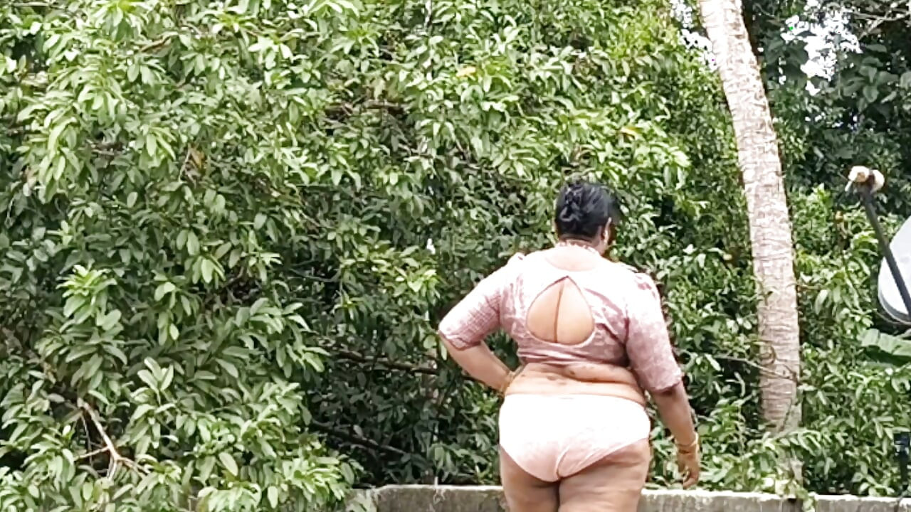 Eine füllige Frau in weißem Rock und pinkem Top zieht sich aus und läuft nackt draußen herum.