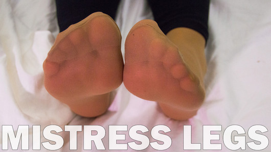 Mistress feet in soft nylon socks is resting on the bed