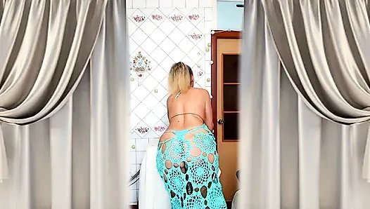 A mature blonde in a knitted dress shows off her curves in a home environment.