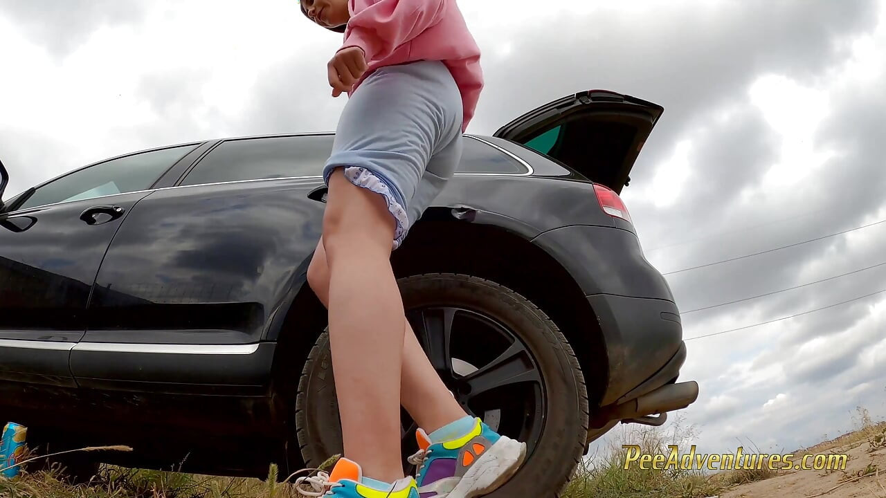 Menina hipster faz xixi com as pernas abertas ao ar livre