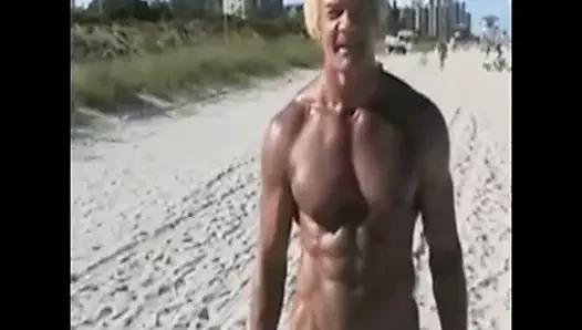 Yaşlı bir adam çıplaklar plajına büyük beyaz bir horoz gösteriyor
