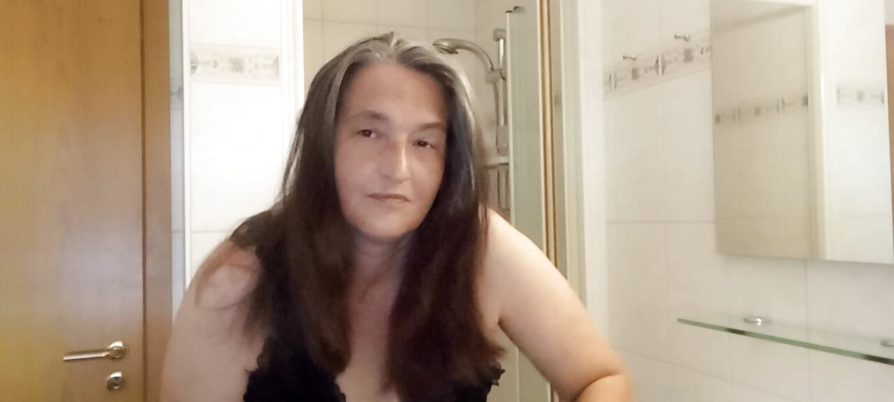 Mature woman with real silver strands slowly combs her long hair