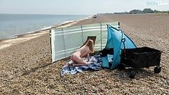 Eine junge blonde ehefrau ist nackt und masturbiert an einem öffentlichen britischen strand