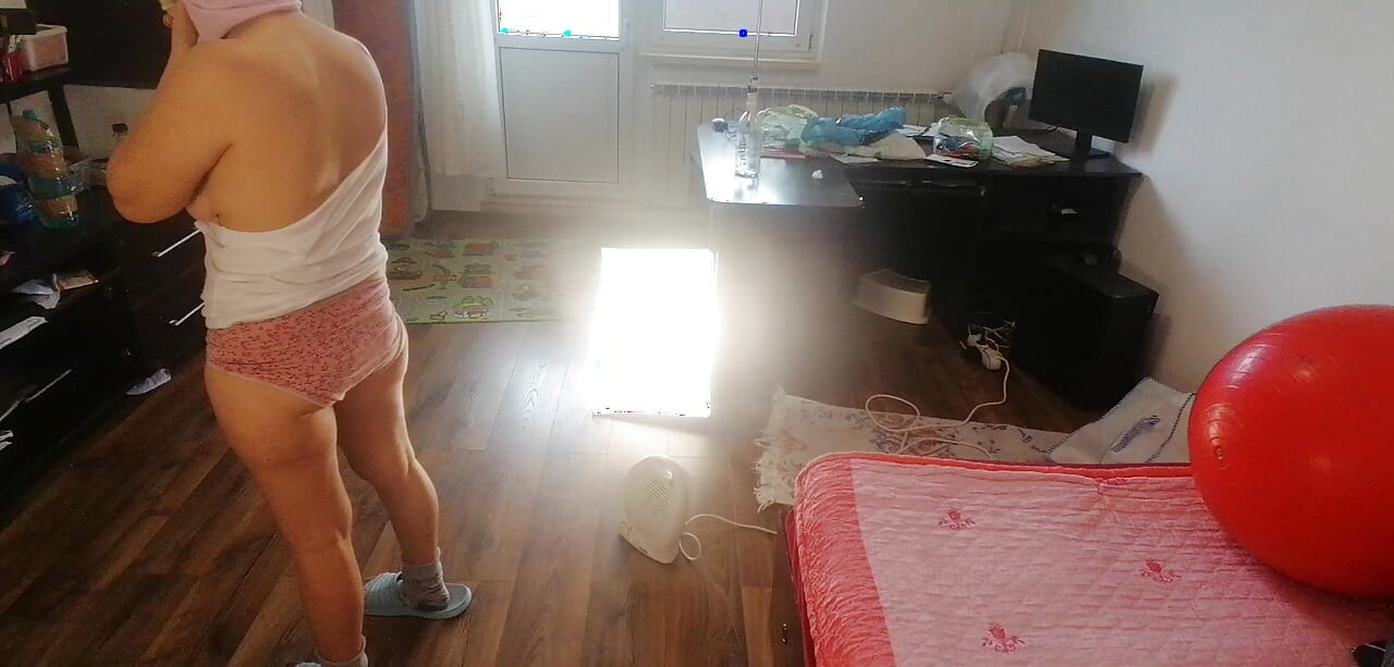 Amateur-ehefrau tanzt nackt zu hause. Amateur-frau hat spaß, Kleidung anprobieren und zu schneiden.