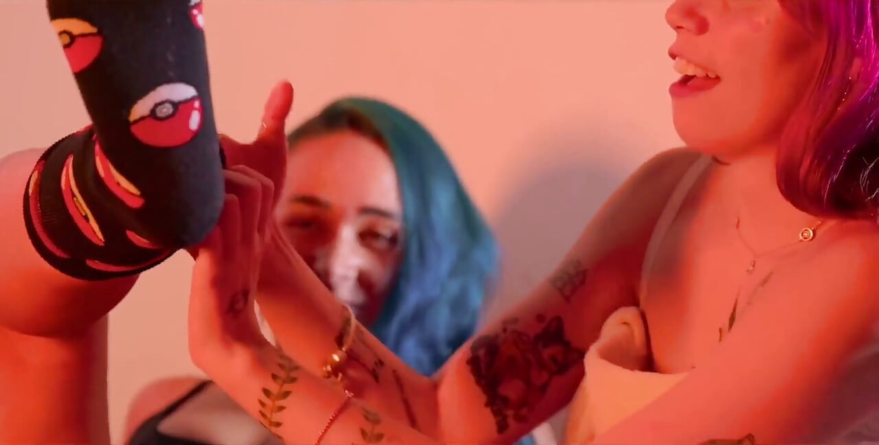 De pele clara, meninas tatuadas esfregando e lambendo os pés pequenos uma da outra.