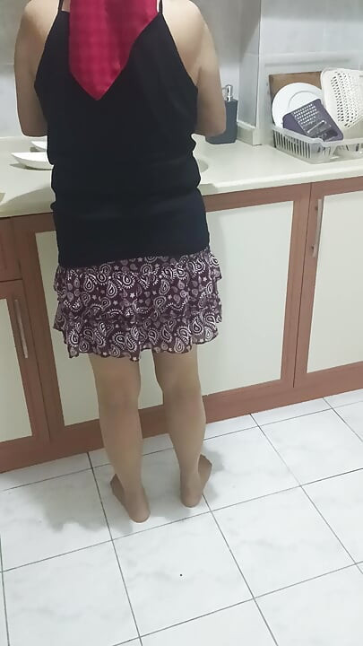 Mature woman in sheer stockings doing housework in the kitchen.