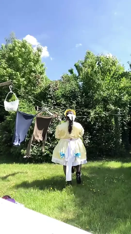 In an outfit with a yellow and blue maid dress to hang the laundry.