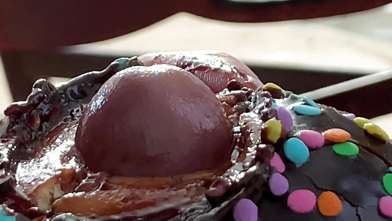 Comendo preto chocolate Pau coberto de esperma donut &sprinkles