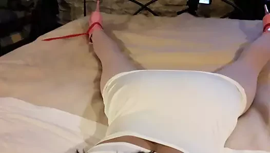 Laura is wearing a sexy white dress, pink pantyhose and platform heels, tied up and gagged in a bed