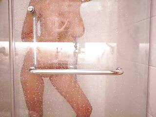 一个性感的金发女郎洗澡并抚摸自己