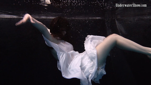 Ambiance sombre à la piscine avec une fille en robe blanche