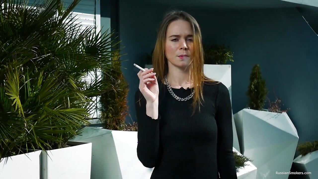 Jovem russa fumando cigarro à beira-mar