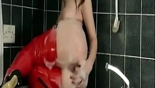 Rotes latex-schätzchen fingert ihre tropfnasse muschi