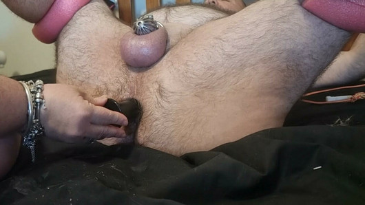 Mrs Chonk stretching Mr Chonk's ass with buttplugs while he wears a cock cage and is tied up