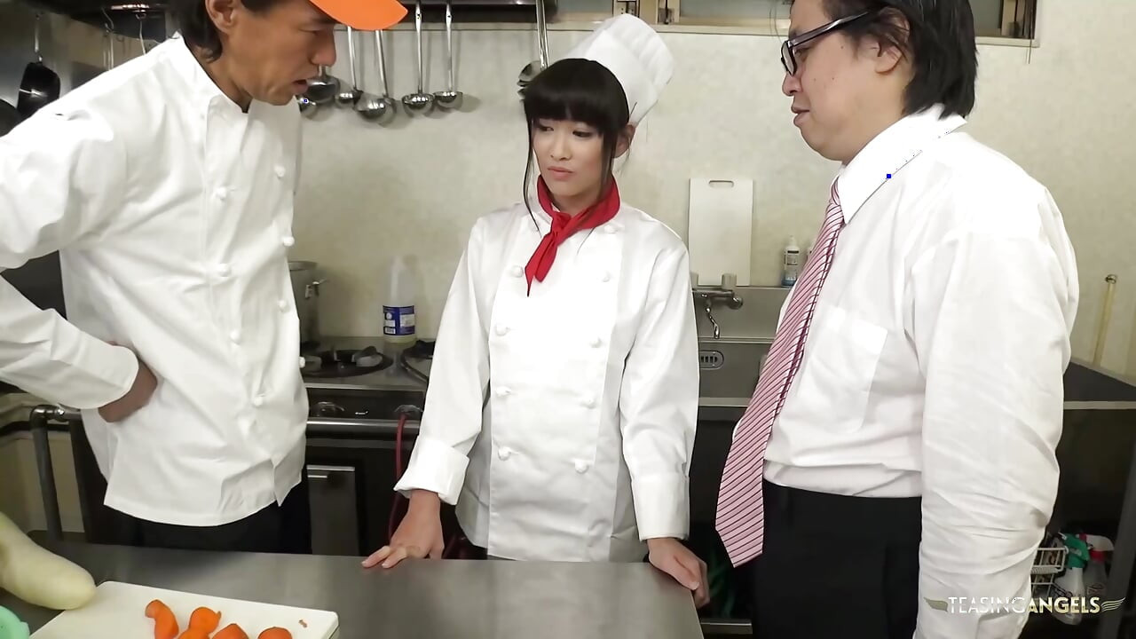 O chef e a gerência do restaurante repreendem o cozinheiro asiático instruindo-a a apertar vegetais grossos