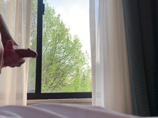 Harde pik aftrekken in het raam van een hotelkamer.