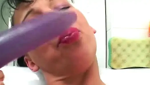 Brünette spielt mit lila dildo in der wanne ihre muschi