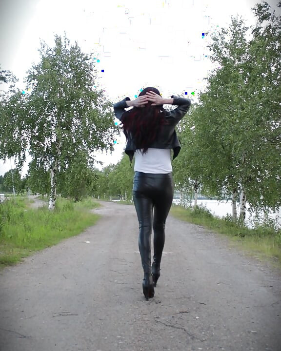 Elle marche dans une tenue en cuir et des talons.