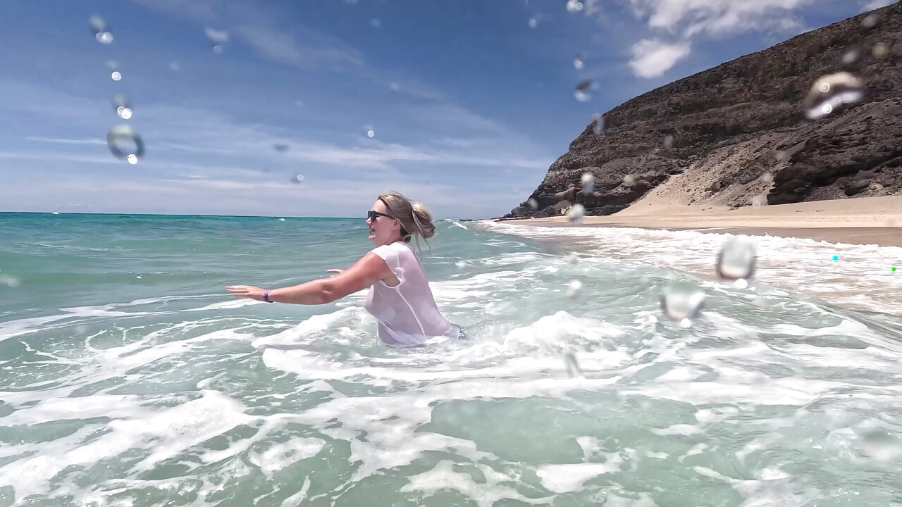 Fată umezind blugii în ocean și înotând în tricou alb umed