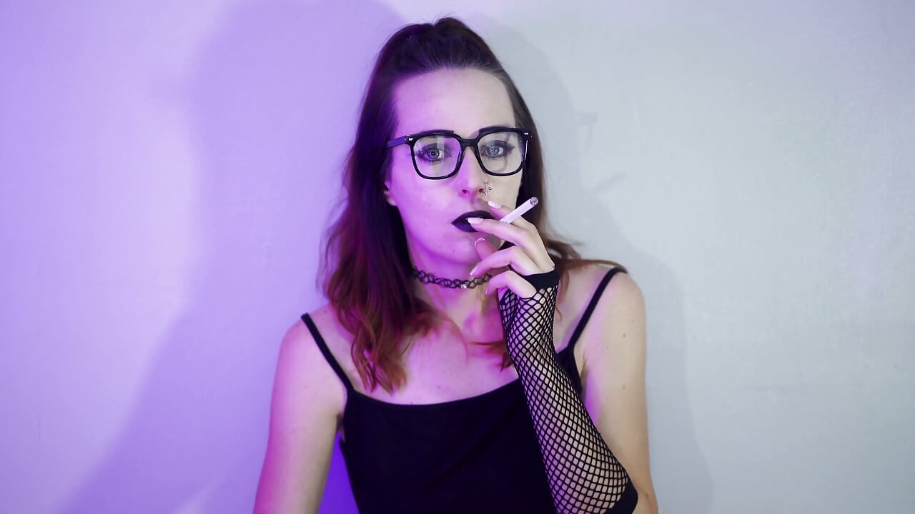 Menina gótica fumando em meia arrastão