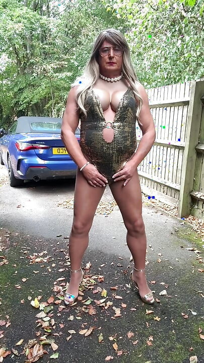 Seksi transvestit kellycd2022 u zlatnom kupaćem kostimu i štiklama čisti lišće