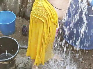 Indische Hausfrau, die draußen badet