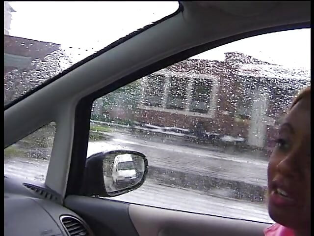 Opgepikte zwarte vrouw met gekleurd haar geeft een lekkere pijpbeurt aan een chauffeur