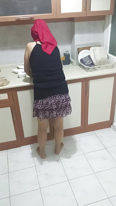 Mature woman in sheer stockings doing housework in the kitchen.