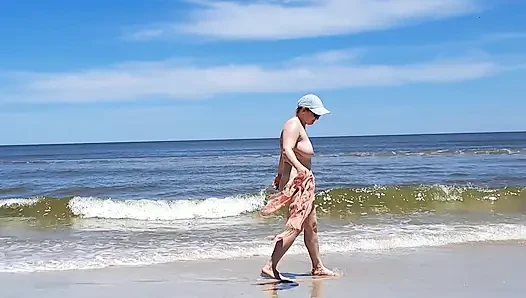 Amateur filming. A nudist plays with waves on the ocean shore.