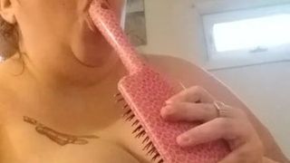 Porquinha da limpeza chupando o cabo da escova de cabelo