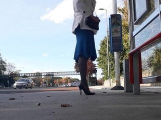 Menggantungkan stiletto paten hitamku sambil menunggu di halte bus