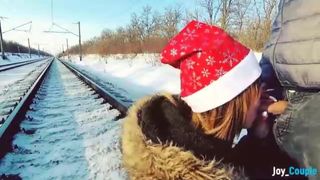 Une fille en manteau de fourrure fait une pipe sur la voie ferrée