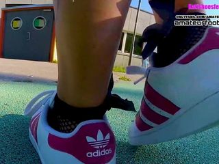 Dziewczyna w czerwonych gwiazdach Adidasa robi buty, maczając kabaretki