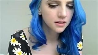 Une fille aux cheveux bleus en fleurs joue avec des seins