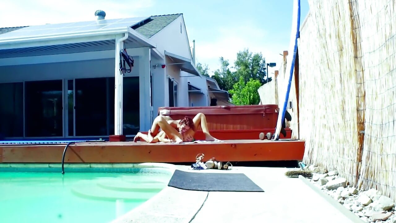 Nua no deck da piscina quente - morenas magras lambem e se dedam no sol do meio-dia