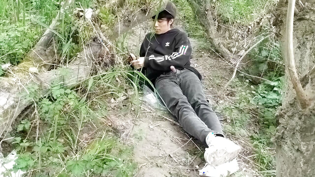 The cute gay twink jerking off his cock, pulled through his fly while outdoors, is Jon Arteen