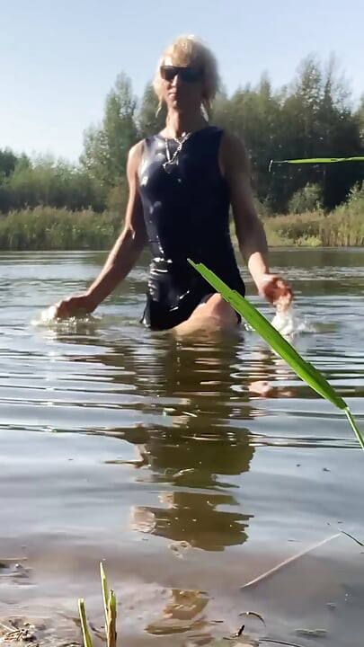 Trans djevojka pliva u jezeru u plavoj sportskoj haljini. Wetllok trans djevojka mokra.