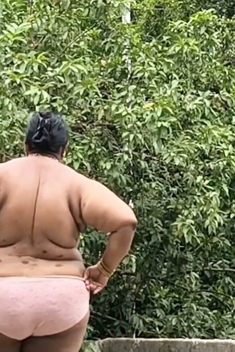 Beyaz etekli ve pembe tombul kız tamamen soyunuyor ve açık havada çıplak yürüyor