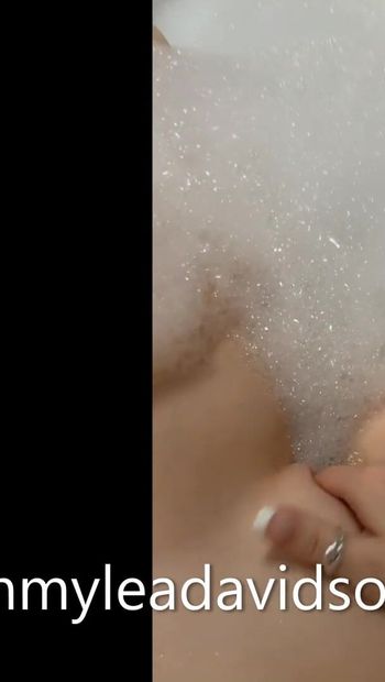 Une jeune nymphomane joue avec sa chatte dans la baignoire d'hôtel avec des bulles