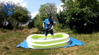 Cachorro ciclista en piscina - refrescándose y pateando